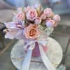 Soft pink roses and pale pink lilies form a cuddly, rounded bouquet