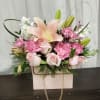 Pink and white floral arrangement in a pale gift box with a gold chain handle