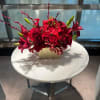 A lush cluster of deep red roses and red lilies makes an