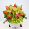 Orange tulips and green orchids in a white vase