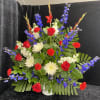 A bold upright spray of red roses, red gladiolus, white spider mums