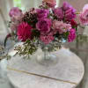 A lush, compact centerpiece of pink and purple roses and soft carnations-Spring