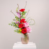 Red and pink roses in a ribbed glass vase with branching stems