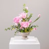 Pink tulips arranged in a pedestal vase with small yellow accents