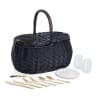 Black wicker picnic basket with plates, glasses, and gold utensils