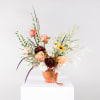 Mixed bouquet with peach roses and dark blooms in a terracotta vase