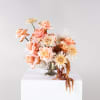 Peach roses and cream blooms arranged in a gold vase