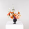 Peach and orange flower arrangement in a black vase
