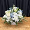 White and pale blue floral arrangement in a white basket