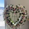 Heart-shaped standing wreath of white chrysanthemums and pale pink roses on a metal easel.