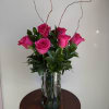 Pink roses arranged in a clear glass vase with tall curly branches