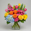 Mixed bouquet in a clear glass vase with roses, tulips, hydrangea, and daisies