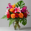 Bouquet of red and orange roses with pink lilies in a glass vase