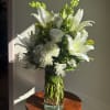 White lilies and roses arranged in a clear glass vase