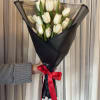 Bouquet of white tulips wrapped in black paper with a red ribbon