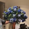 Large blue floral arrangement with roses and daisy-like blooms