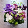 Purple orchids and white roses arranged in a low bouquet