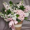 A soft and elegant blush pink flower arrangement featuring lush hydrangeas, delicate