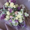 A delicate and romantic bouquet featuring soft lilac blooms, elegant white roses