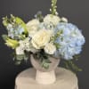 A dreamy mix of fluffy hydrangeas, classic white roses, and textured accents