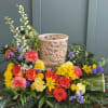 A bright, celebratory centerpiece arranged around a decorative candle holder, this cremation