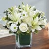 A serene cluster of white lilies, roses, and daisy-like blooms creates a