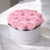 A refined round white hat box showcasing soft blush pink roses, each