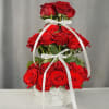 Tiered arrangement of red roses in a white box with ribbon bows