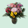 Mixed pink and yellow flowers arranged in a glass vase