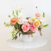 Pink and peach flower arrangement in a white container