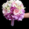 A tightly rounded handheld bouquet in soft pinks, whites, and lavender makes