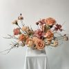 Peach roses and pink flowers arranged in a white vase