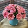 Rounded cluster of pink garden roses (with greenery) in a turquoise ceramic
