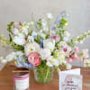 Mixed pastel bouquet in a clear glass vase beside a candle and thank-you card
