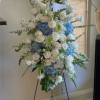 A tall, formal standing spray arranged on a black metal easel, this