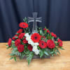 Red and white floral arrangement with a clear glass cross centerpiece