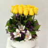Yellow roses and white orchids arranged in a white vase