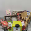 A beautifully curated basket filled with chocolates, coffee set, tea, dipped pretzels