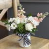 Soft white roses and cheerful white daisies mingle with peach stock flowers