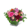 Pink and purple rose arrangement in a square glass vase