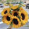 Handheld bouquet of bright yellow sunflowers