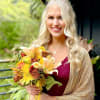 Woman holding a bouquet of yellow, orange, and white flowers