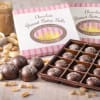 Box of chocolate peanut butter balls with open tray of truffles and scattered peanuts