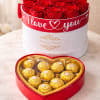 Red roses in a round box with a heart-shaped chocolate box in front