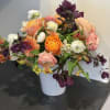Mixed bouquet of orange, pink, white, and purple flowers in a white vase