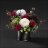 Metal cylinder filled with hydrangea, ranunculus, spray roses, thistle, dianthus, trachelium,
and wax