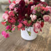 Pink and burgundy flowers arranged in a white vase