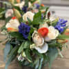 Bouquet of white roses, orange tulips, and blue hyacinths in a glass vase