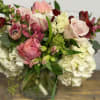 Mixed bouquet of pink, white, and burgundy flowers in a glass vase