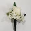 White rose boutonniere with baby's breath and dark greenery
